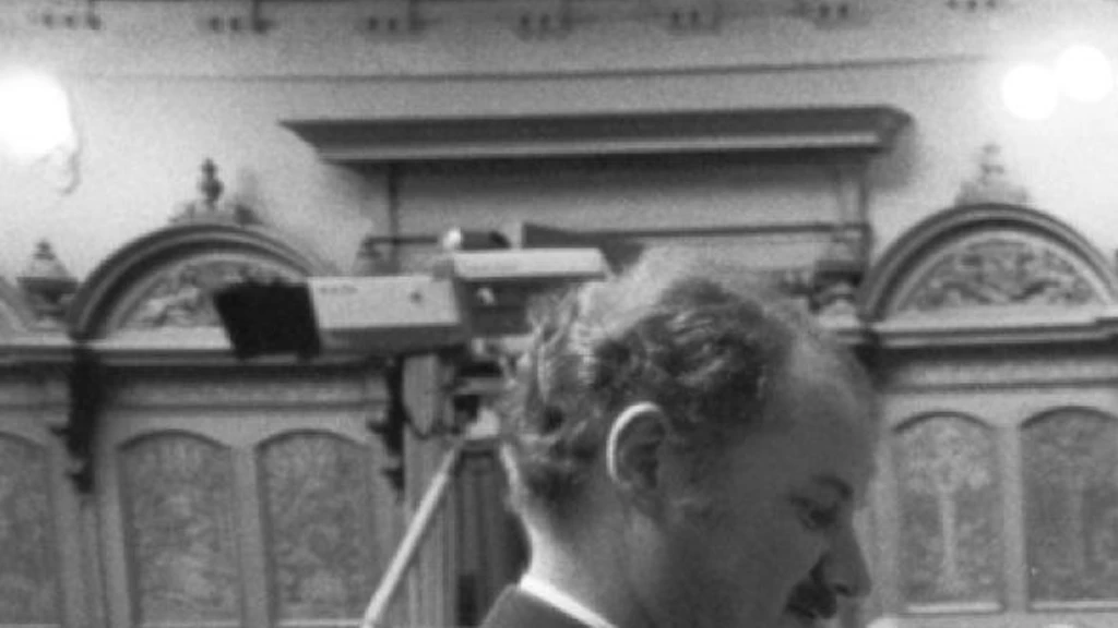 Alt-Bundesrat Arnold Koller gibt in einem schwarz-weiss Bild seine Stimme in der Bundesversammlung ab. Die Szene zeigt den Moment vor seiner Wahl in den Bundesrat; ein uniformierter Beamter hält die Urne, während Koller und weitere Parlamentsmitglieder ihre Stimmzettel einwerfen.