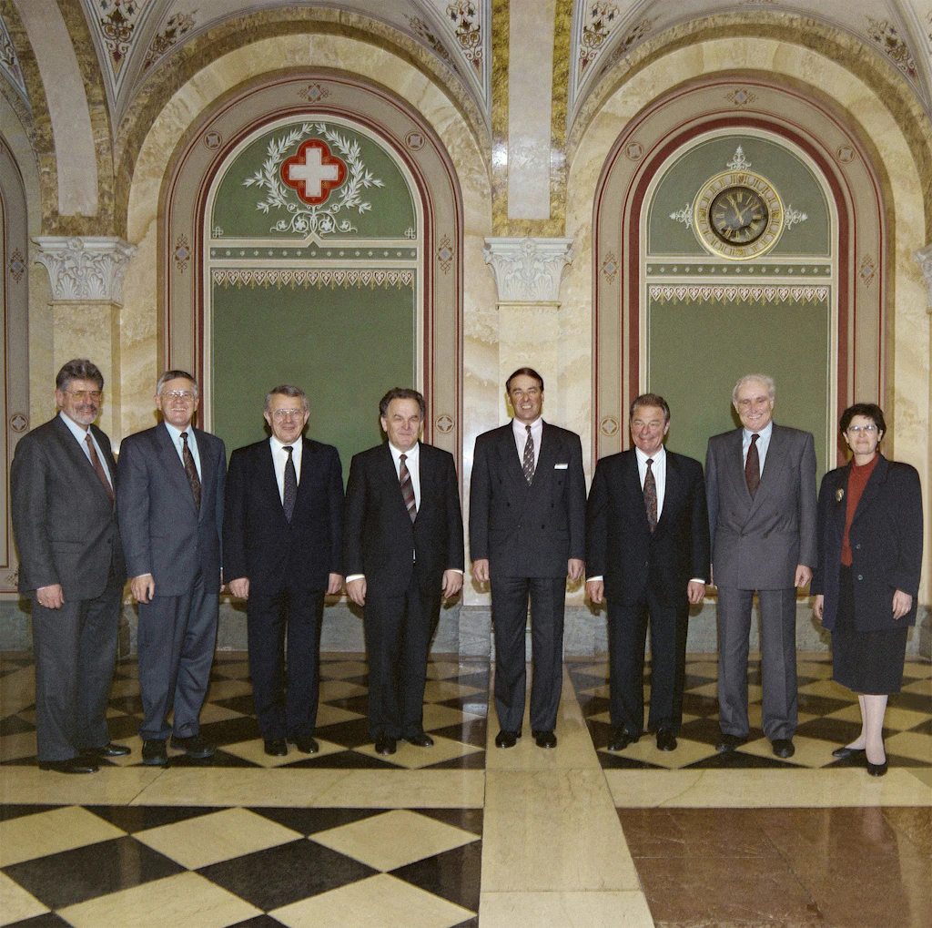 Le Conseil fédéral 1993 in corpore (de gauche à droite): le chancelier de la Confédération François Couchepin, le conseiller fédéral Kaspar Villiger, le conseiller fédéral Arnold Koller, le conseiller fédéral Otto Stich, le président de la Confédération Adolf Ogi, le conseiller fédéral Jean-Pascal Delamuraz, le conseiller fédéral Flavio Cotti, la conseillère fédérale Ruth Dreifuss